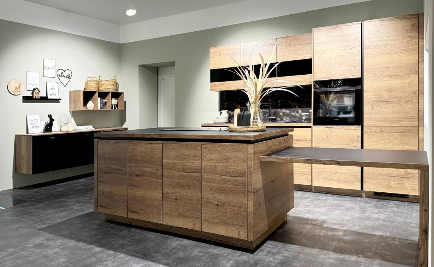 Elegante Küche mit Holzinsel und Schränken, Akzentbeleuchtung und dekorativen Elementen auf grauem Untergrund.