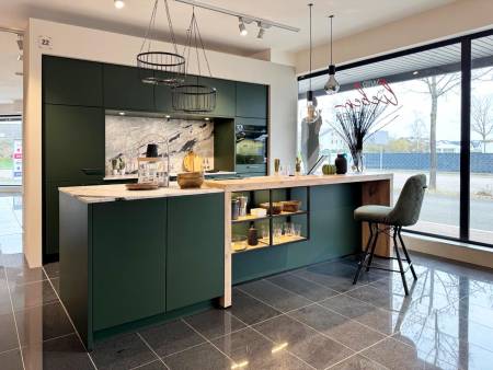 Moderne grüne Küche mit zentraler Insel und Marmoroptik, umgeben von stilvollen Hängelampen und Glasfronten.