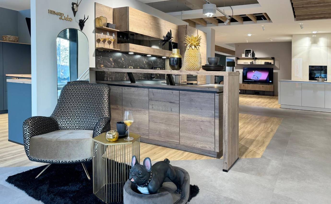 Schicker Wohnraum mit gemustertem Sessel und Holzküche, akzentuiert durch einen schwarzen, flauschigen Teppich und Ananas-Dekor.