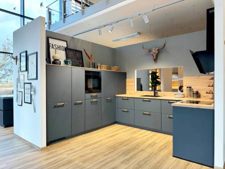 Schicke Küche im Loft-Stil mit graublauen Schränken, Holzakzenten, dekorativen Schildern und einer Metallskulptur in Form eines Stierkopfes über dem Spülbereich.